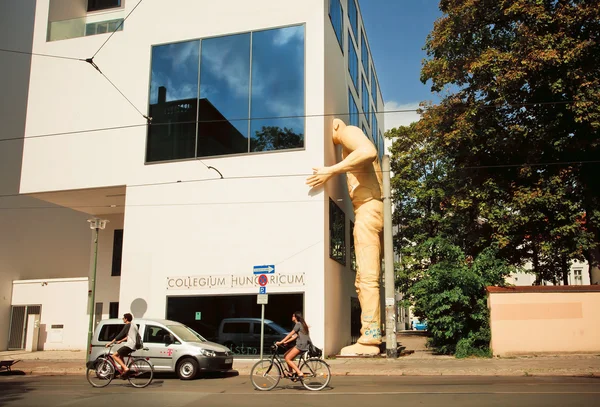 Los ciclistas conducen más allá de la escultura gigante de un hombre espiando — Foto de Stock