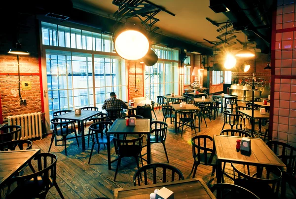 Lonely man sitting in huge room of empty bar with modern design — Stock Photo, Image