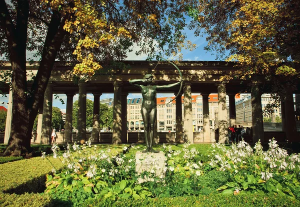 Pomnik lekkoatletka z łukiem i strzałą w ogrodzie z kwiatami — Zdjęcie stockowe