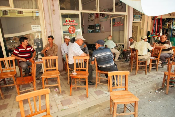 Senior men sitting around tables and talking in rustic cafe of village — Stock Photo, Image