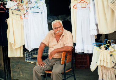 İhtiyar bir adamın iç çamaşırı satan ve eski Türk köy sokak pazarında kıyafet 