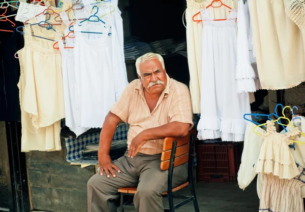 Elderly man sells lingerie and clothes on street market of old turkish village — Stock Photo, Image