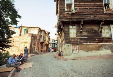 Poor people sitting on the cobbled street with old wooden buildings of turkish capital 