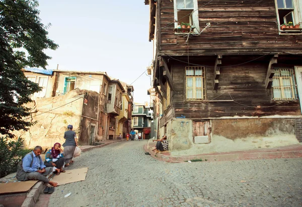 Бедные люди сидят на мощеной улице со старыми деревянными зданиями турецкой столицы — стоковое фото