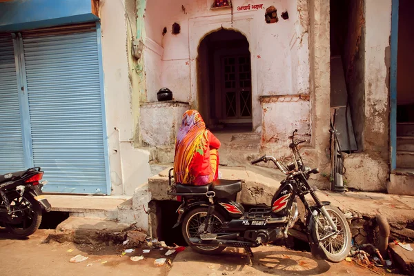 Indian lady sitting on motorbike on poor people area of old city — Stock Photo, Image