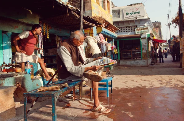 Senior sitting outdoor and reading an indian newspaper on the street — Stock Photo, Image