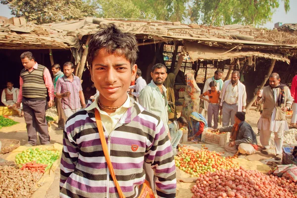 Неизвестный подросток, стоящий в толпе клиентов деревенского овощного рынка в Индии — стоковое фото