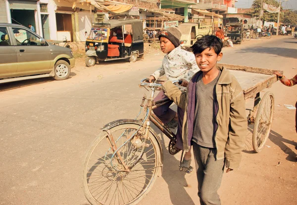 Unidentified children driving on bicycle cart through dirt indian street in India — 图库照片