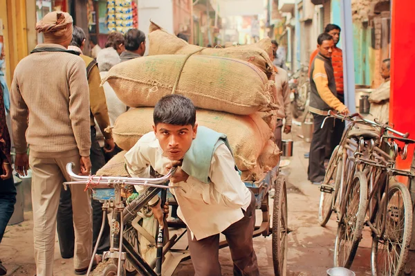 Travailler dur jeune homme porte de lourds sacs de fret sur vélo vintage — Photo