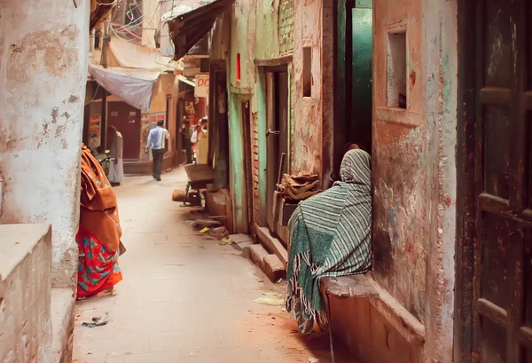 Arme Menschen in langen traditionellen Schals sitzen auf der Grunge-Straße der alten indischen Stadt — Stockfoto