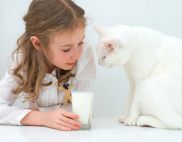 Malá holčička sdílet sklenici mléka s kočkou. — Stock fotografie
