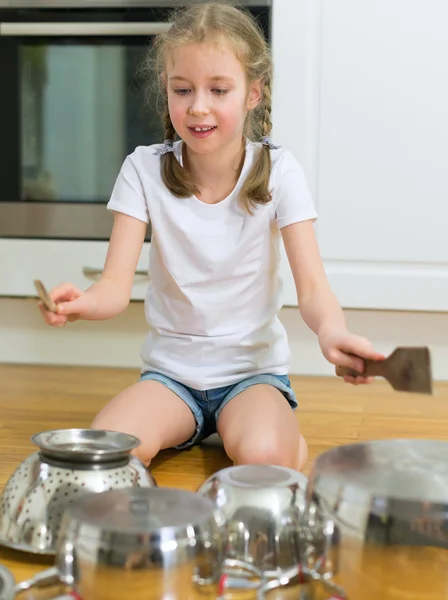 Menina tocando bateria em panelas e panelas na cozinha . — Fotografia de Stock