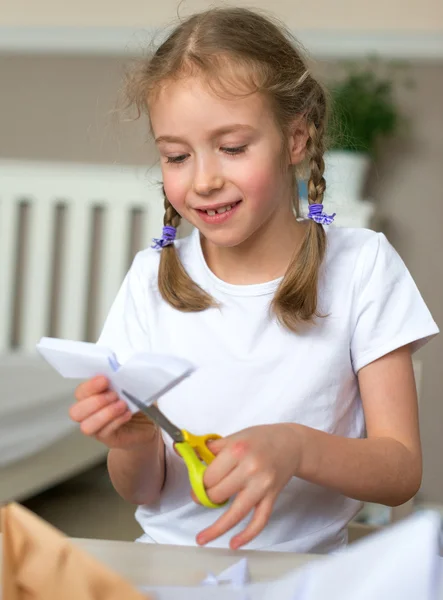 Little girl with scissors cut paper at home. — Stock Photo, Image