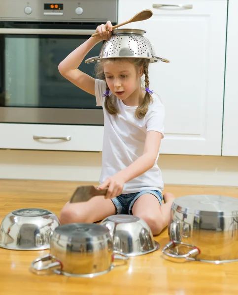 Menina tocando bateria em panelas e panelas na cozinha . — Fotografia de Stock