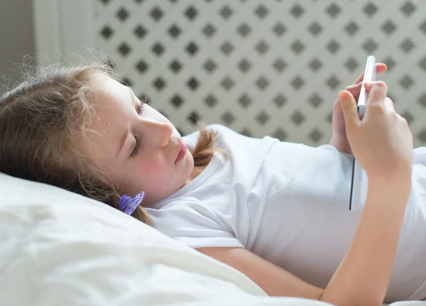 Meisje met de tablet pc in bed liggen. — Stockfoto