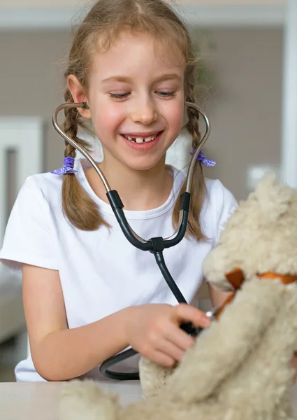 Cute little girl playing in doctor with her toy. — Stock Photo, Image