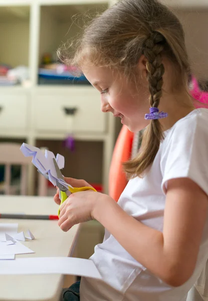 Dziewczynka z nożyczkami cięta papier w domu. — Zdjęcie stockowe