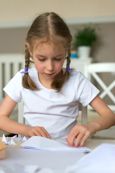 Kleines Mädchen bastelt Papierflieger zu Hause. — Stockfoto