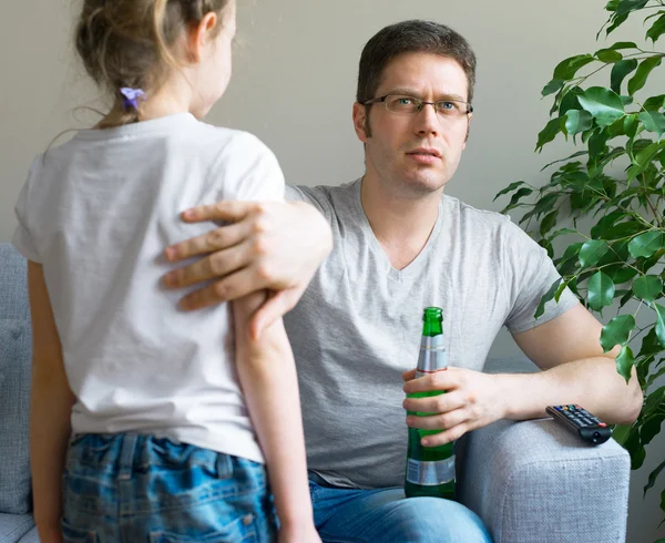 Little girl disturbing her dad while he is watching TV. — Stock Photo, Image