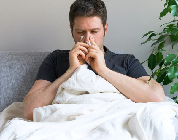 Malade se mouchant alors qu'il était allongé sur son lit à la maison . — Photo