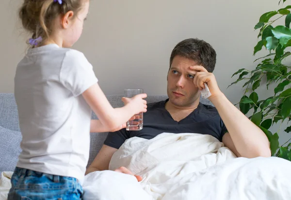 Kleines Mädchen kümmert sich um kranken Vater. — Stockfoto