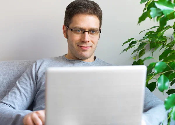 Homem relaxante com computador portátil no sofá . — Fotografia de Stock