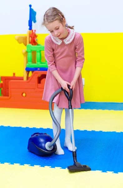 Petite fille avec aspirateur dans la salle de jeux . — Photo