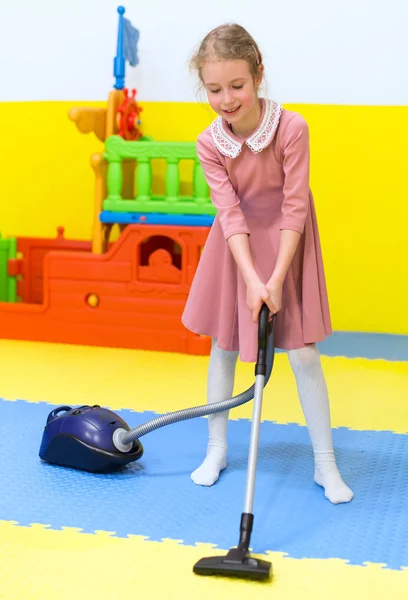 Menina com aspirador de pó na sala de jogos . — Fotografia de Stock