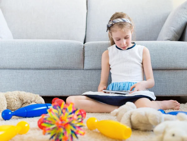 Het is tijd om schoon te maken uw speelgoed! Meisje speelt met de tablet-pc, niet wilt doen de schoonmaak. — Stockfoto