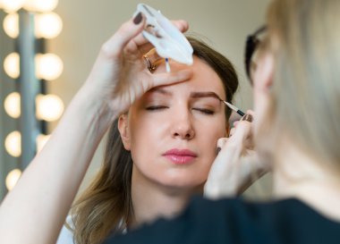 Makyöz modelinin yüzünde makyaj uygulamak.