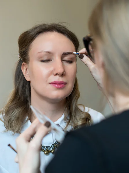 Make-up artist cleaning skin on model's face.