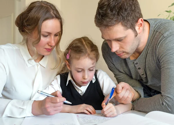 Moeder en vader dochter helpen met huiswerk thuis. — Stockfoto