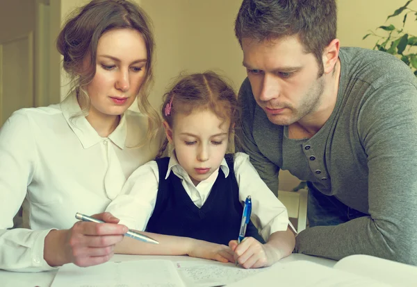 Madre y padre ayudando a su hija con la tarea en casa . —  Fotos de Stock