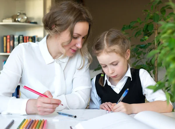 Moeder helpen dochter met huiswerk thuis. — Stockfoto