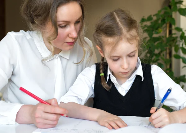 Moeder helpen dochter met huiswerk thuis. — Stockfoto