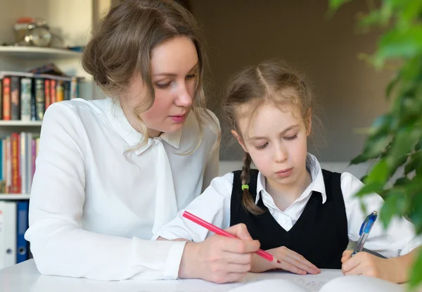 Moeder helpen dochter met huiswerk thuis. — Stockfoto