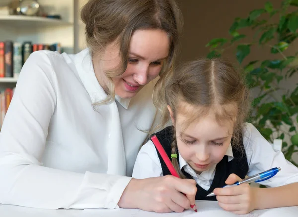 Mère et fille souriantes faisant leurs devoirs à la maison . — Photo