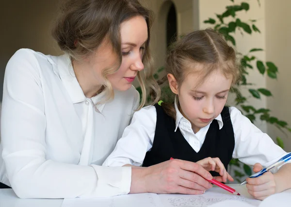 Mother helping daughter with homework at home. — Stock Photo, Image