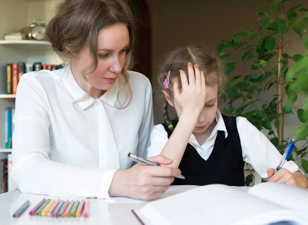 Mère aidant sa fille fatiguée avec des devoirs à la maison . — Photo