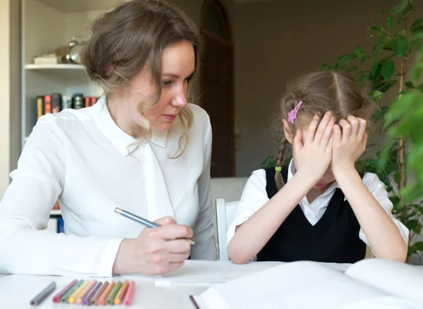 Moeder haar moe dochter helpen met huiswerk thuis. — Stockfoto