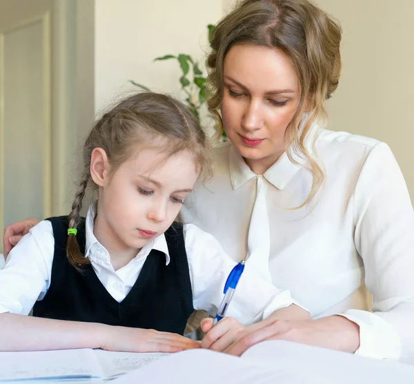 Moeder helpen dochter met huiswerk thuis. — Stockfoto