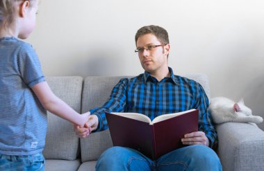 Küçük kız babası kitap okurken rahatsız.