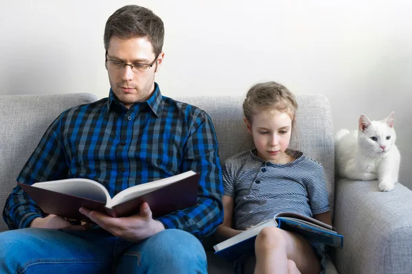 Far och hans dotter läsa böcker på soffa. — Stockfoto