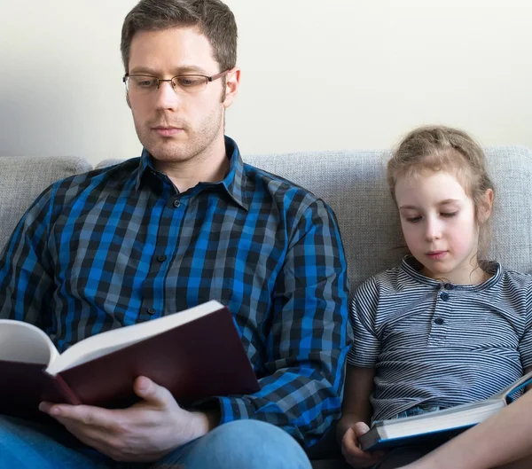 Père et sa fille lisent des livres sur le canapé . — Photo