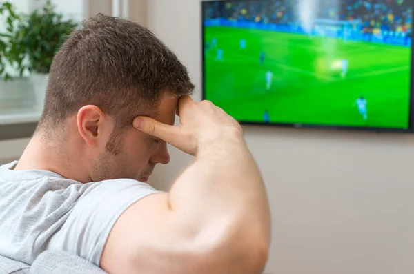 Trauriger Mann schaut Fußballspiel zu Hause im Fernsehen. — Stockfoto