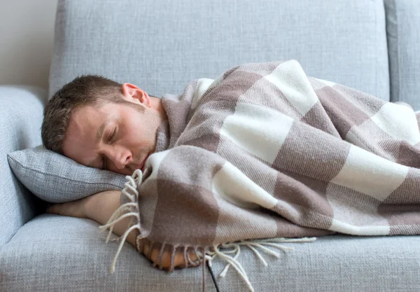 Giovane uomo stanco e dormire sul divano . — Foto Stock