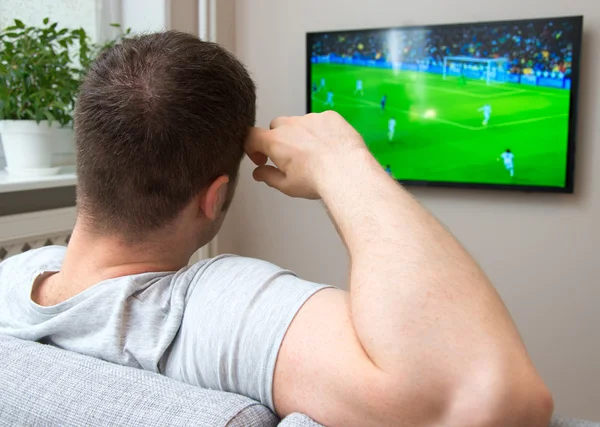 Mann ser på fotballkamp på TV hjemme . – stockfoto