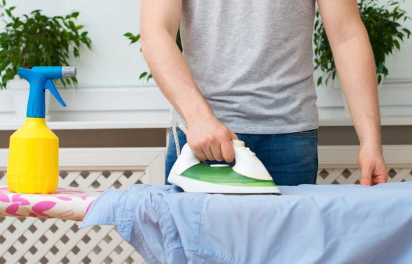 Hombre planchando ropa en la tabla de planchar en casa . —  Fotos de Stock