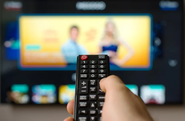 Mano masculina sosteniendo control remoto tv . — Foto de Stock