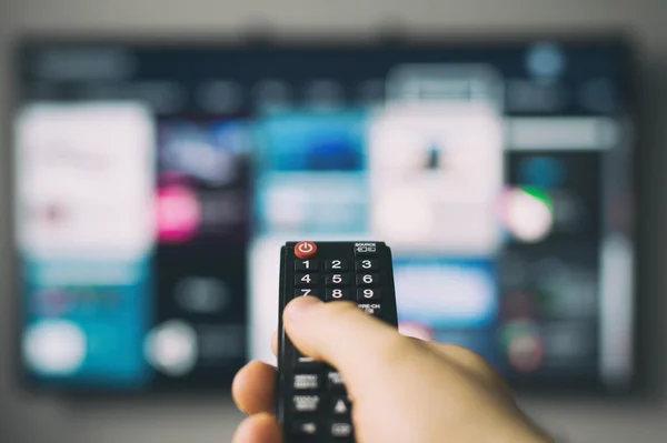 Male hand holding TV remote control. — Stock Photo, Image